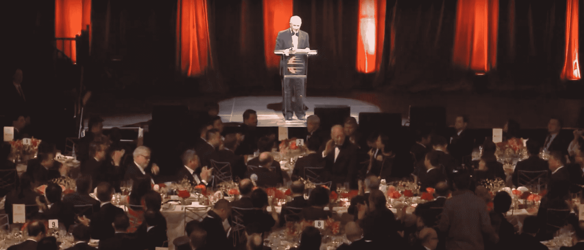 Stephen Schwarzman stands at the podium while Tung Chee-hwa waves to the audience around him during the 2018 China General Chamber of Commerce New Year gala. [YouTube/Screenshot/ChinaGeneralChamberOfCommerceUSA]