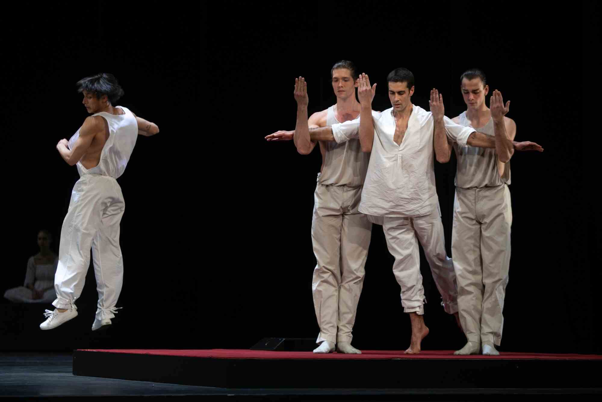Zwei männliche Tänzer stützen einen dritten, seine Arme senkrecht.