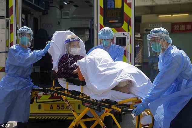 Medizinisches Personal, das PSA trägt, bringt einen älteren Patienten aus einem Krankenwagen in ein Krankenhaus in Hongkong