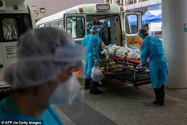 Eine Person wird am 10. März 2022 vor dem Queen Elizabeth Hospital in Hongkong in einen Bus gebracht, da die Regierung angekündigt hat, dass das Krankenhaus nur für Covid-19-Patienten genutzt wird