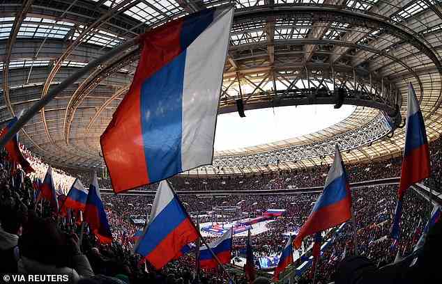Menschen schwenken russische Flaggen während eines Konzerts im Moskauer Luschniki-Stadion, das acht Jahre nach dem letzten Angriff Russlands auf die Ukraine begangen wurde