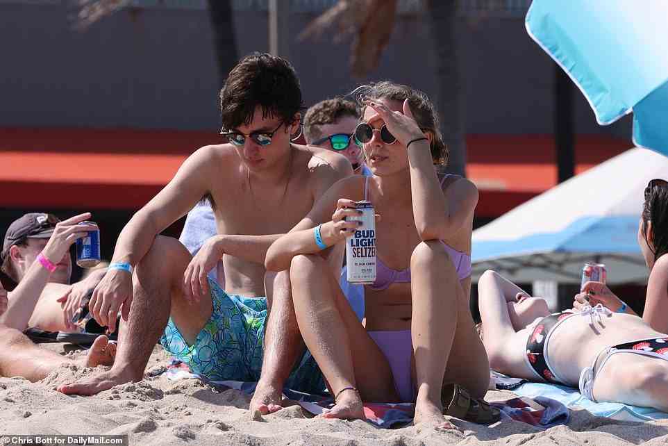 Eine Gruppe von Studenten trinkt Bier, während sie sich während der Spring Break 2022 am Strand von Fort Lauderdale entspannen
