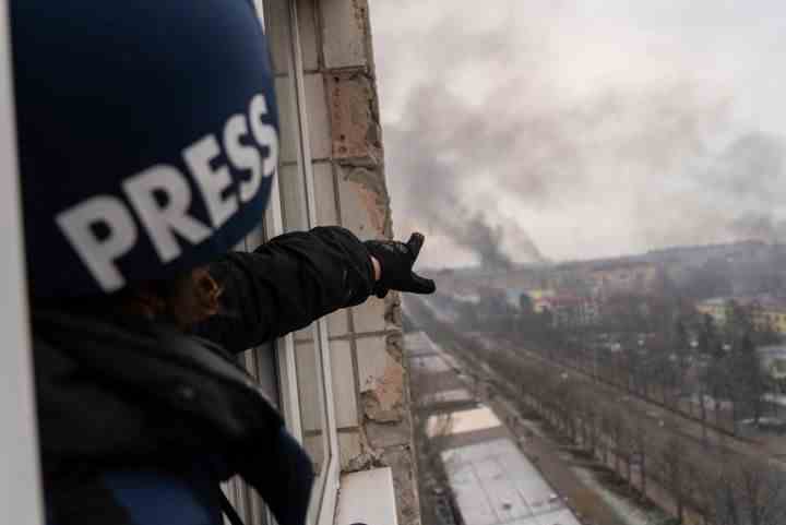 Associated Press photographer Evgeniy Maloletka points at the smoke rising after an airstrike on a maternity hospital, in Mariupol, Ukraine, on March 9, 2022. 