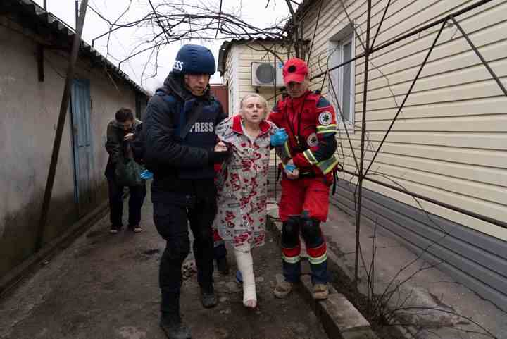 Associated Press photographer Evgeniy Maloletka helps a paramedic to transport a woman injured during shelling in Mariupol, eastern Ukraine, on March 2, 2022. (AP Photo/Mstyslav Chernov)