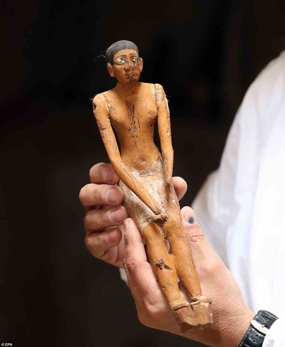 Der Generalsekretär des Supreme Council of Antiquities (SCA) in Ägypten hält eine Figur im Grab eines Mannes namens Henu in der Gegend von Sakkara in der Nähe von Gizeh.