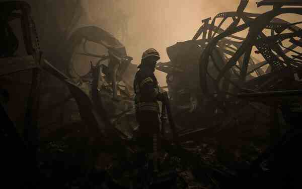 Emergency workers inside a smoky space surrounded by twisted metal curves.