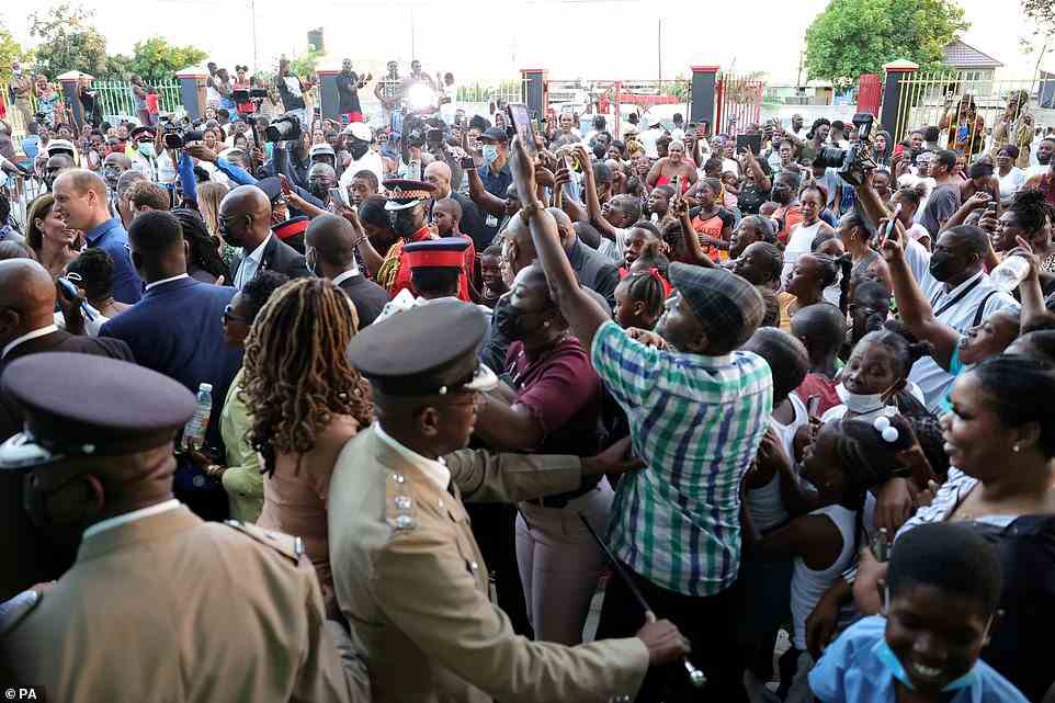 The royals (pictured on the left hand side of the image) were mobbed by Jamaicans who wanted to see them