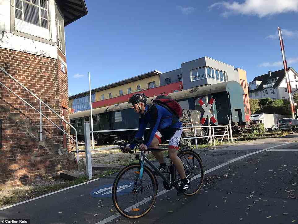 A cyclist on the Vennbahn at the former Walheim station, still with barriers and carriages, in Aachen