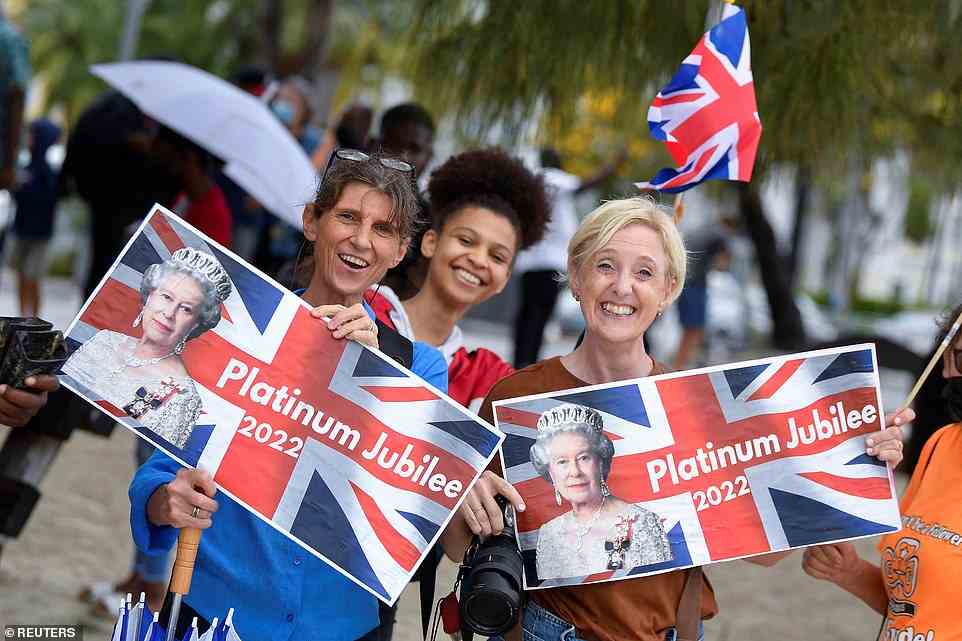 Pictured: Well-wishers cheer and wave at the arrival of Prince William and his wife Kate, holding up Union jack flags with the Queen's face on to celebrate her Platinum Jubilee