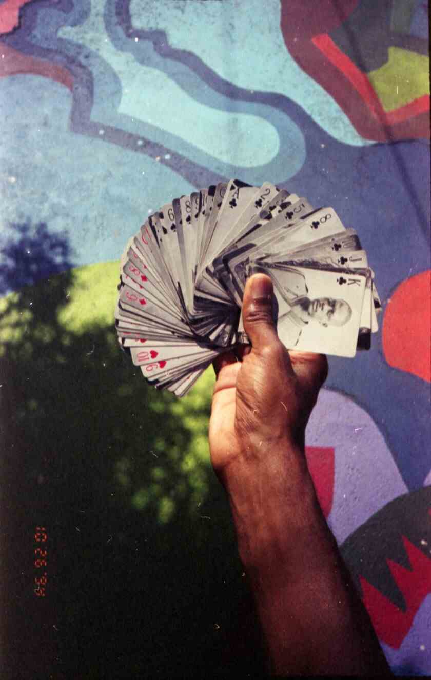 Eine Hand fächert Karten mit Tintype-Porträts auf.