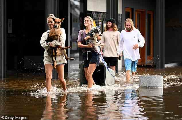 Concerns are growing for the future of Byron Bay as destructive flash flooding continues to wreak havoc in the popular holiday town (pictured, people walk through floods on Wednesday)