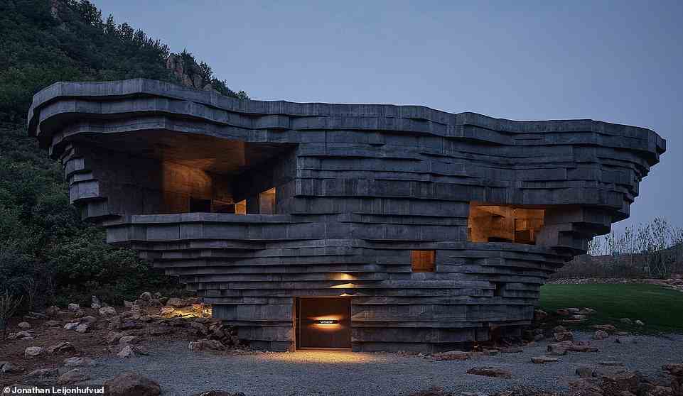 Abgebildet ist eine spektakuläre neue Konzerthalle in China, die so gestaltet wurde, dass sie wie ein „mysteriöser Felsbrocken aussieht, der sanft an seinen Platz gefallen ist“.