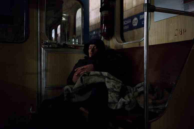 Ein Mann schläft in einem Auto einer Kiewer U-Bahnstation, die von Menschen als Luftschutzbunker genutzt wird.