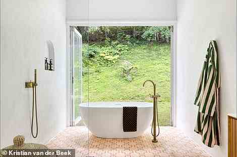The bathroom has a huge free-standing bath and shower space by the floor-to-ceiling glass doors that open out onto the forest