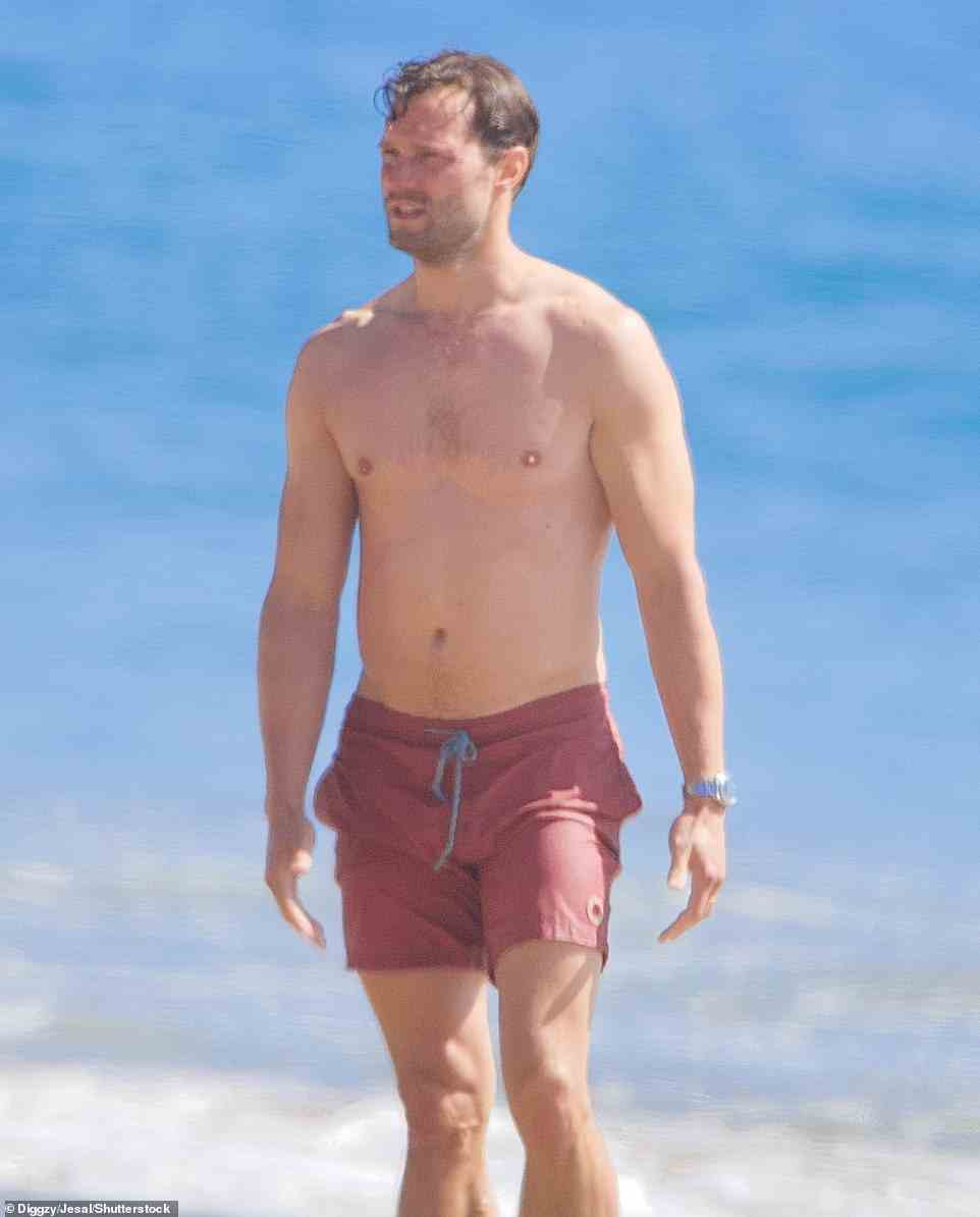 Summer ready: Fifty Shades of Grey star Jamie showed off his chiselled physique as he larked about on the sand, wearing a pair of salmon pink swimming shorts