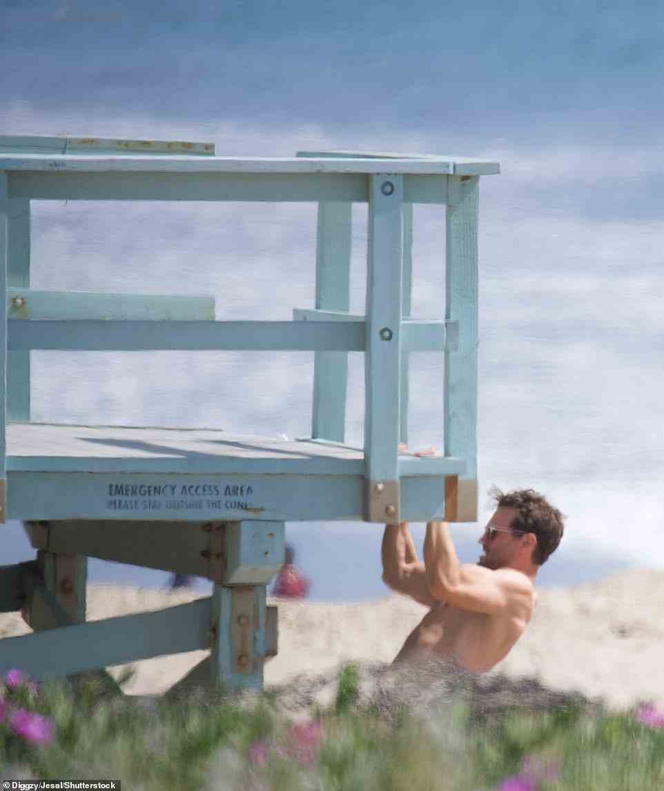 Keeping fit: At one point, the Northern Irish star was seen demonstrating his strength has he performed pull-ups on the side of a wooden lifeguard tower