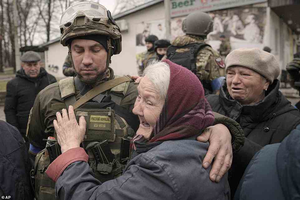 A woman hugs a Ukrainian serviceman after a convoy of military and aid vehicles arrived in the formerly Russian-occupied Kyiv suburb of Bucha