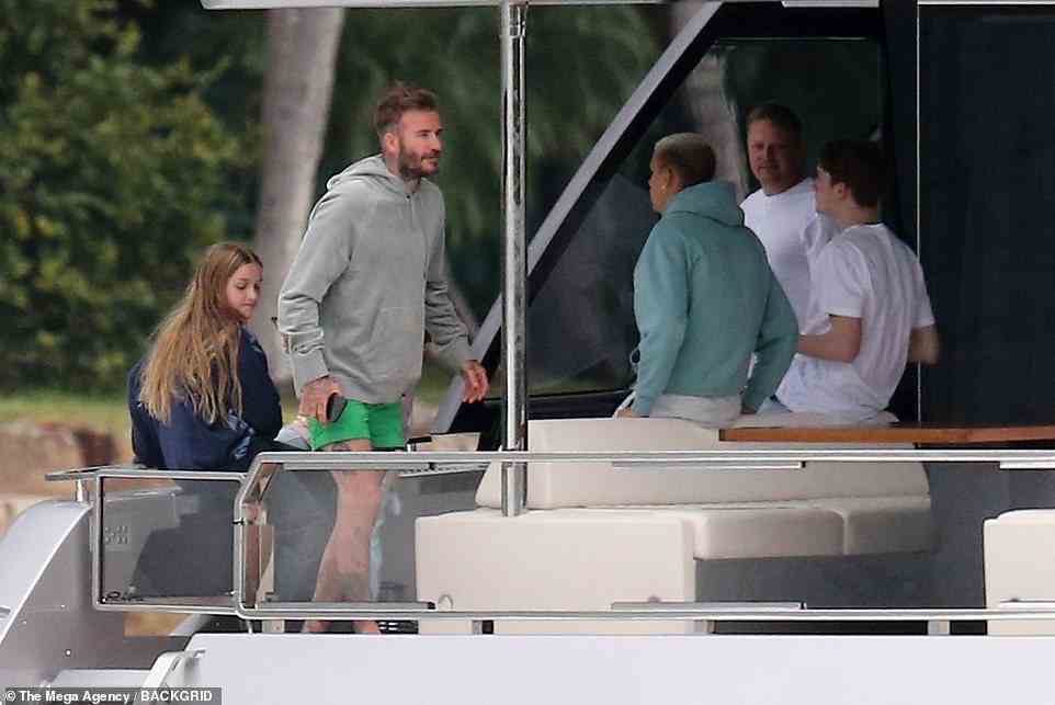 Family: The former professional footballer, 46, kept things casual in a grey hoodie and unmissable green swim shorts, as he chatted to his son, 19, and daughter, 10, on top of the 93.5ft vessel, named Seven, on Monday