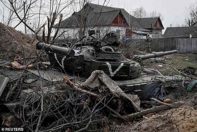 A Ukrainian service member walks near an abandoned Russian tank in Vablya in Kyiv region, April 5, 2022