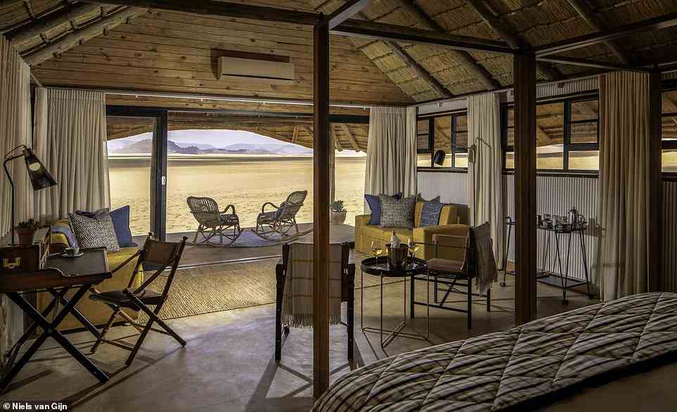 In total, there are 12 canvas bungalows at the camouflaged camp, each 'capped with a golden thatched roof and backed by sunset-red sand dunes'