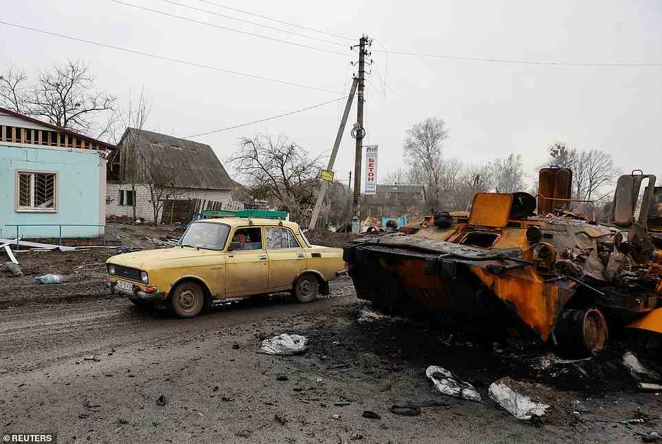 A local resident drives past a destroyed Russian armoured personal carrier, as Russia's attack on Ukraine continues, in the village of Nova Basan