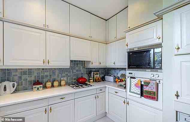 Die Küche hat weiße Wand- und Unterschränke mit einer passenden Werkstatt und blauen Fliesen