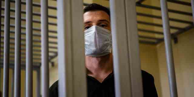 US ex-marine Trevor Reed, charged with attacking police, stands inside a defendants' cage during his verdict hearing at Moscow's Golovinsky district court on July 30, 2020. 