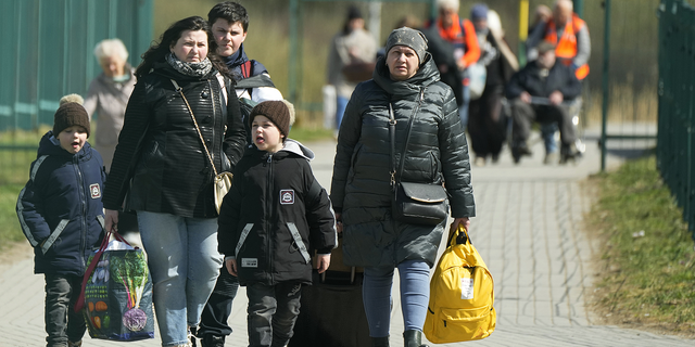 Flüchtlinge laufen nach der Flucht vor dem Krieg aus der benachbarten Ukraine am Freitag am Grenzübergang in Medyka im Südosten Polens.