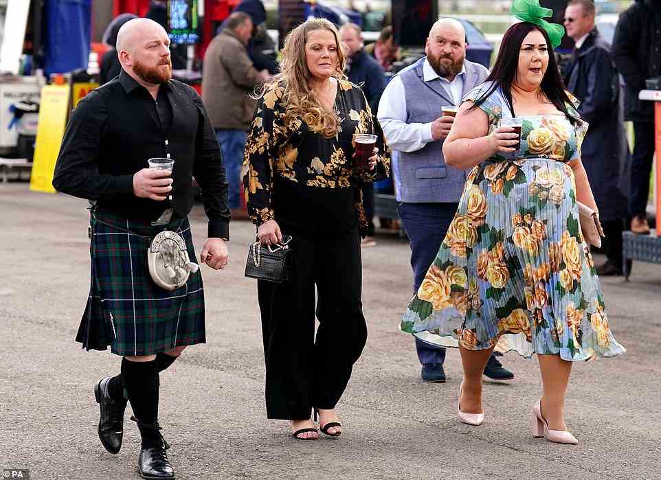 Time for a tipple: revellers were pictured getting into the party spirit, with pints in hand, as they wandered around the raceground