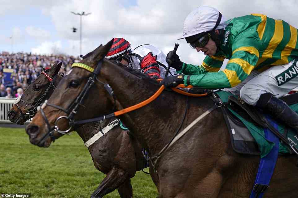 Charlie Todd riding Party Business (pictured left, in red) clear the last to win The EFT Construction Handicap Hurdle at Aintree