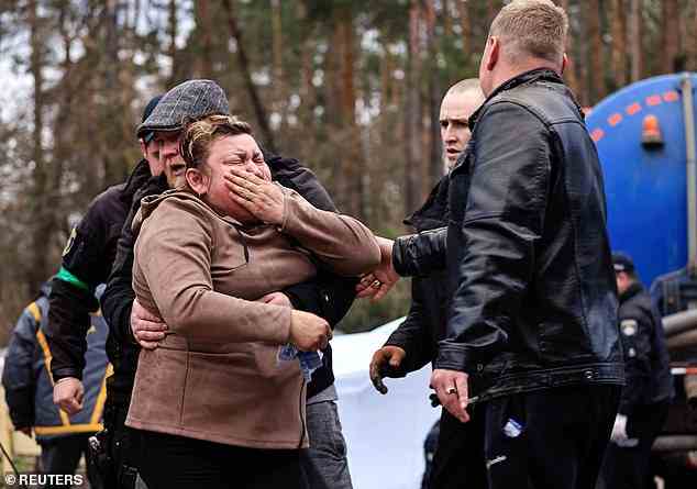 A mother reacts as police members exhume the body of her son, who according to the head of the village was killed by Russian soldiers, from a well at a fuel station in Buzova, on Sunday