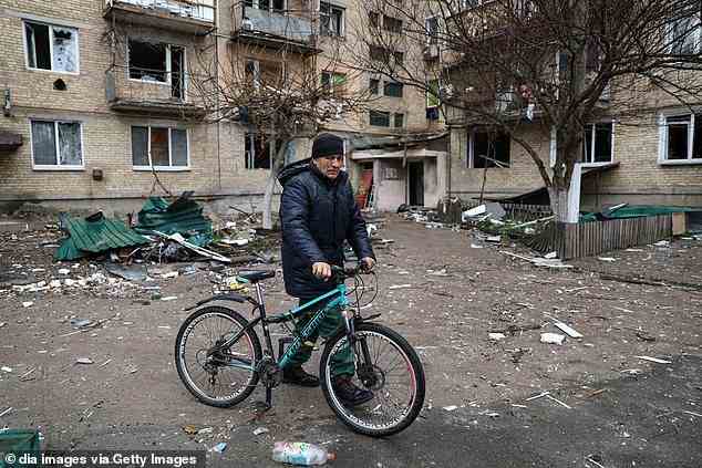A man pushies a bicycle by a buidling severely damaged in attacks by Russian forces in Makariv on Sunday
