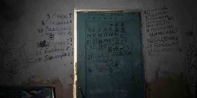 An einer Wand und einer Tür im Keller einer Schule in Yahidne, in der Nähe von Tschernihiw, Ukraine, Dienstag, 12. April 2022, sind Schriftzüge zu sehen.