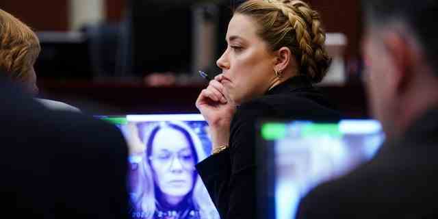 Amber Heard sitzt im Gerichtssaal, während ihre ehemalige persönliche Assistentin Kate James während Johnny Depps Verleumdungsprozess gegen sie per Video aussagt.