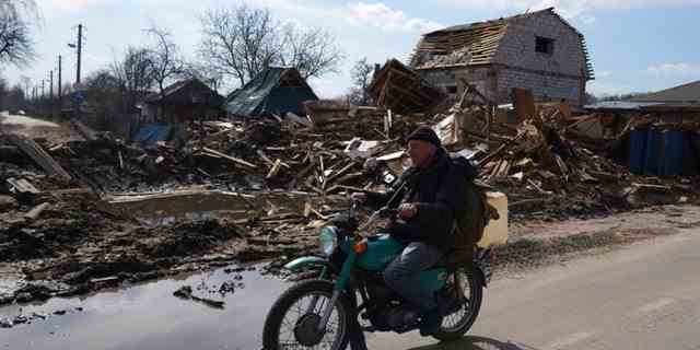 Ein Mann fährt am Donnerstag, den 7. April 2022, mit einem Motorrad an einem durch Beschuss beschädigten Haus in Tschernihiw, Ukraine, vorbei. Die Ukraine fordert die Bewohner ihres industriellen Kernlandes auf, zu gehen, solange sie noch können, nachdem sich die russischen Streitkräfte aus den zerstörten Außenbezirken von Kiew zurückgezogen haben, um sich neu zu formieren eine Offensive im Osten des Landes. 