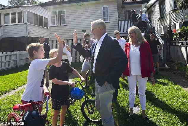 Der australische Oppositionsführer Anthony Albanese begrüßt einheimische Kinder, als er eine Straße inspiziert, die von den jüngsten Überschwemmungen betroffen ist
