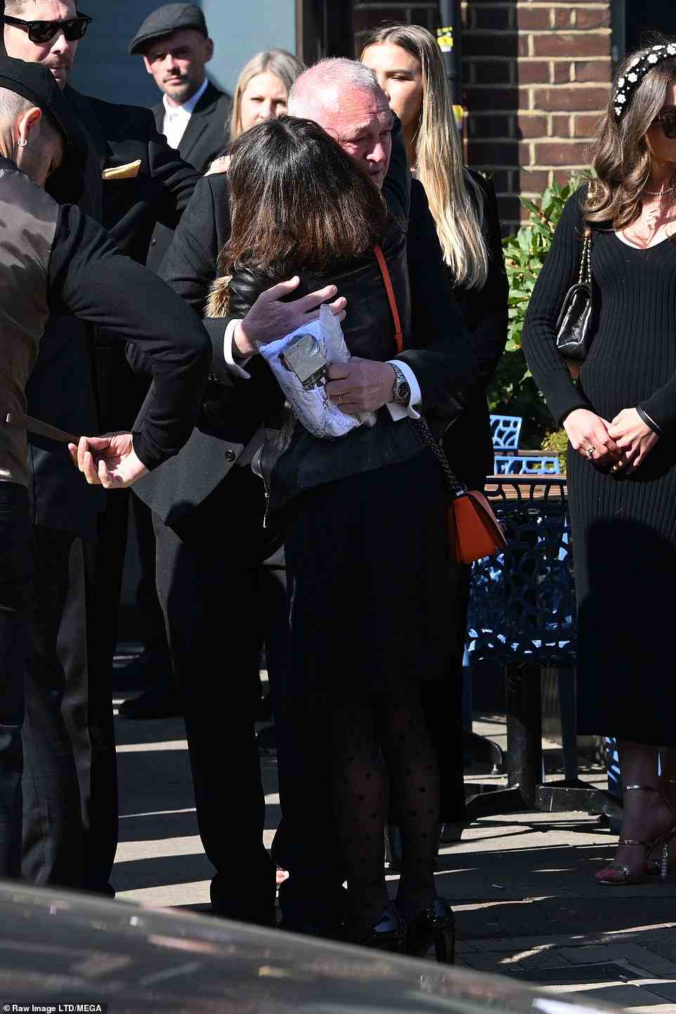 Loved ones: He received a hug from a member of the Parker family after the emotional service was played to hundreds of fans outside the church
