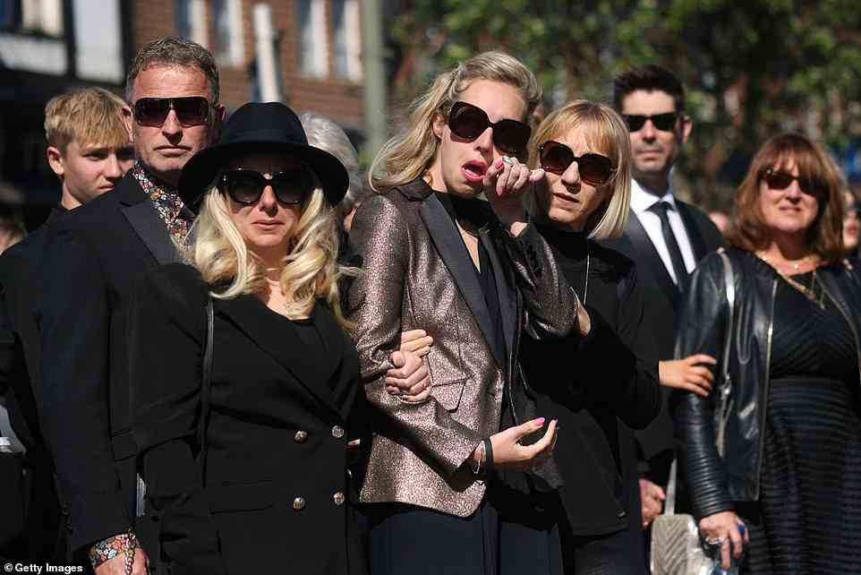 Tears: Earlier, the pop singer's widow, Kelsey, whom he married in 2018, earlier watched the funeral procession with her parents and Tom's mum and dad (right)