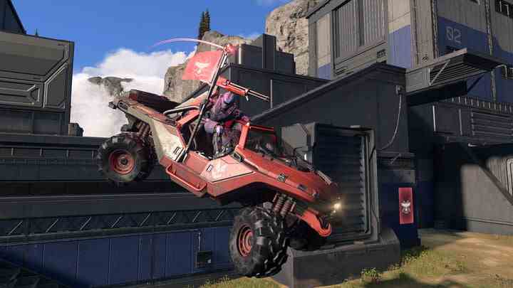 A Spartan holds the enemy flag while riding a Warthog in Halo Infinite.