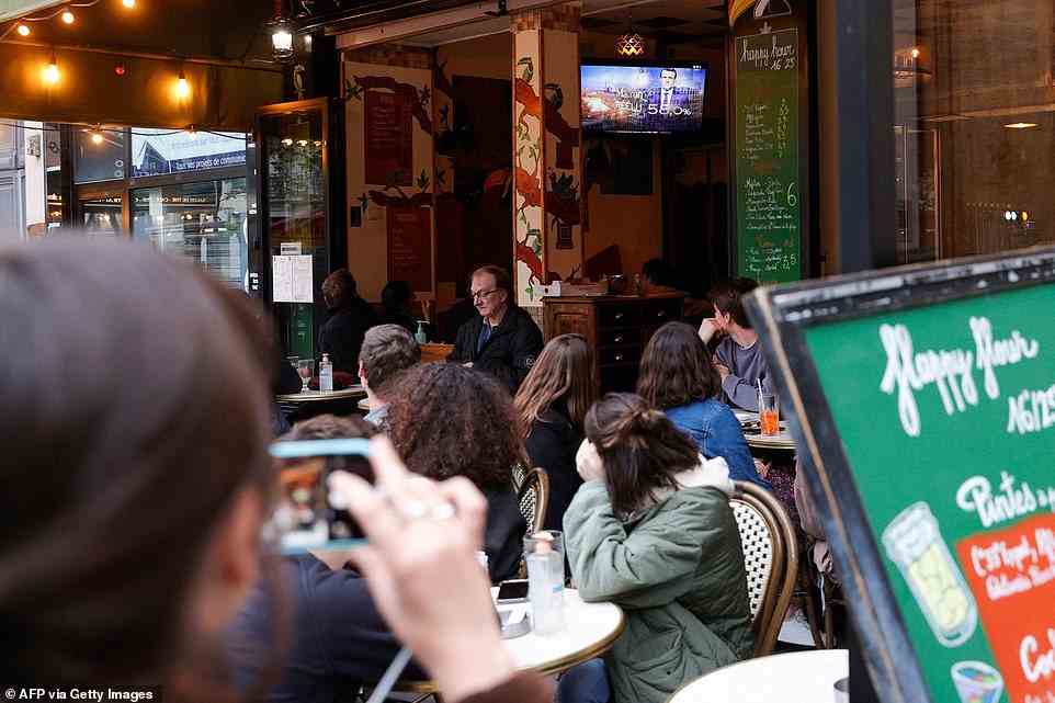 Die Leute sehen in einer Bar vor dem Fernseher, wie die Nachricht kommt, dass Macron gewonnen hat