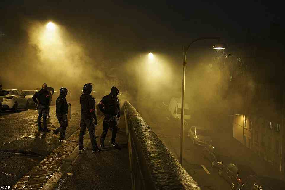 Polizisten stehen in Tränengaswolken, als sie Demonstranten der extremen Linken in Lyon, Zentralfrankreich, verfolgen