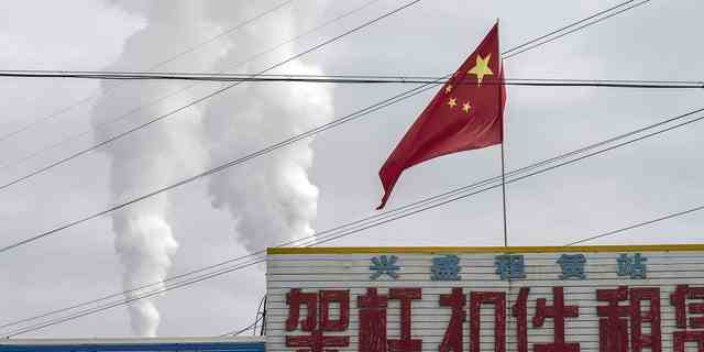 Die chinesische Flagge weht vor Abgasen, die aus einem Kohlekraftwerk in Jiayuguan, Provinz Gansu, China, aufsteigen, 1. April 2021.