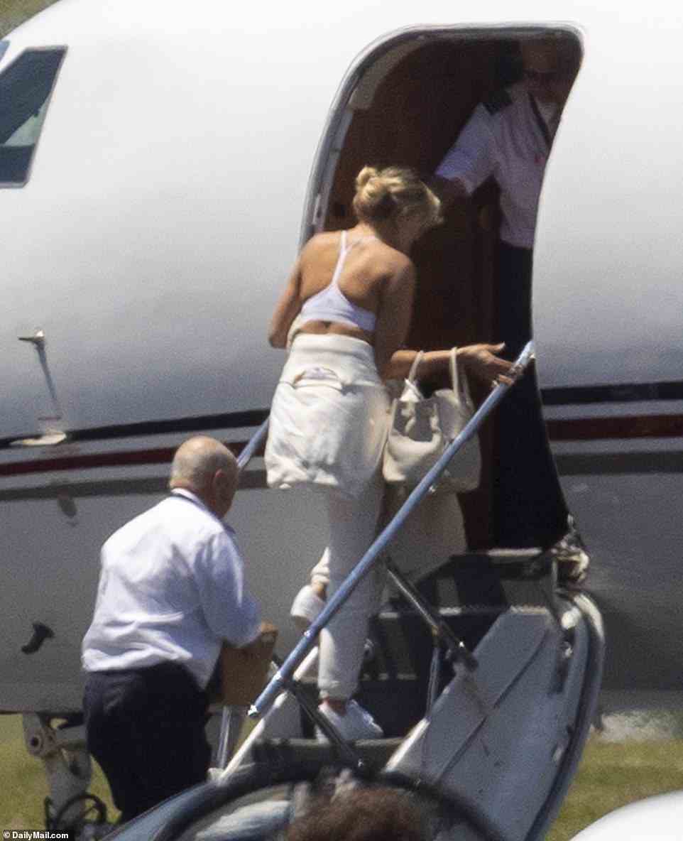 Paulina - all dressed in white - joins her husband as they board a private jet Sunday after getting married in Tennessee