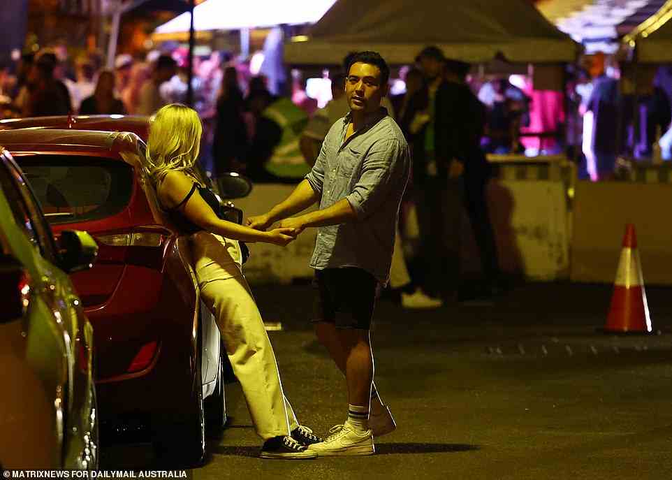 One woman rests against a car as she waits outside pubs with a male friend at the Rocks in Sydney (pictured)