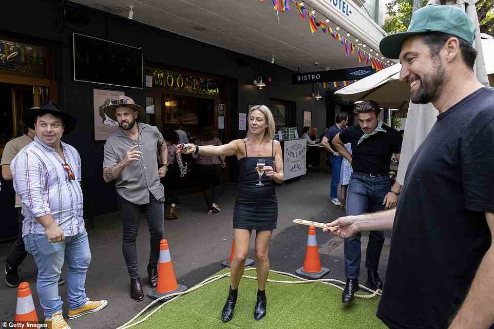 A woman holds out cash as she makes a bet on a game of two-up at the Woolpack Hotel in Redfern
