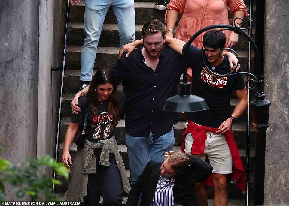 Revellers wrap their arms around each others' shoulders as they leave a venue in Sydney's CBD on Monday afternoon