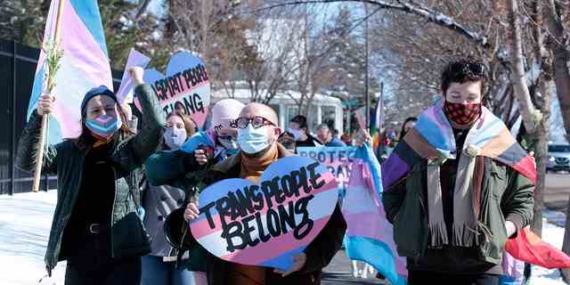 DATEI – Befürworter von Transgender-Menschen marschieren am 11. März 2021 von der Villa des Gouverneurs von South Dakota zum Kapitol in Pierre, SD. 