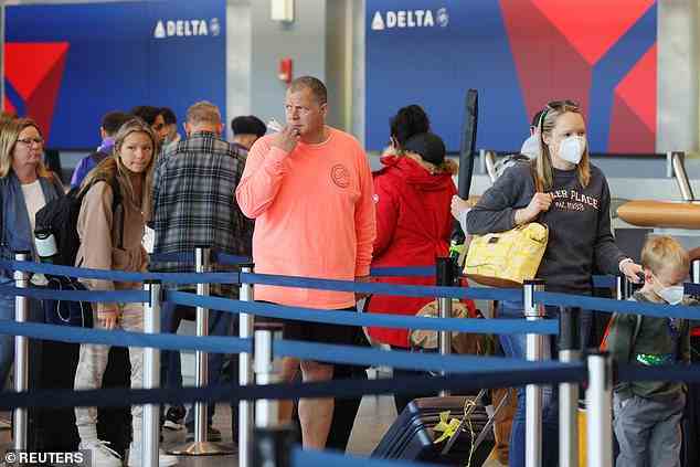 Reisende, die Masken tragen und keine Masken tragen, warten am Dienstag an einem Schalter von Delta Airlines in Boston in der Schlange.  Delta Air Lines sagte am Mittwoch, es plane, Flugprivilegien für etwa 2.000 Kunden wiederherzustellen, die von Flügen ausgeschlossen wurden, weil sie die Maskenregeln nicht eingehalten hatten