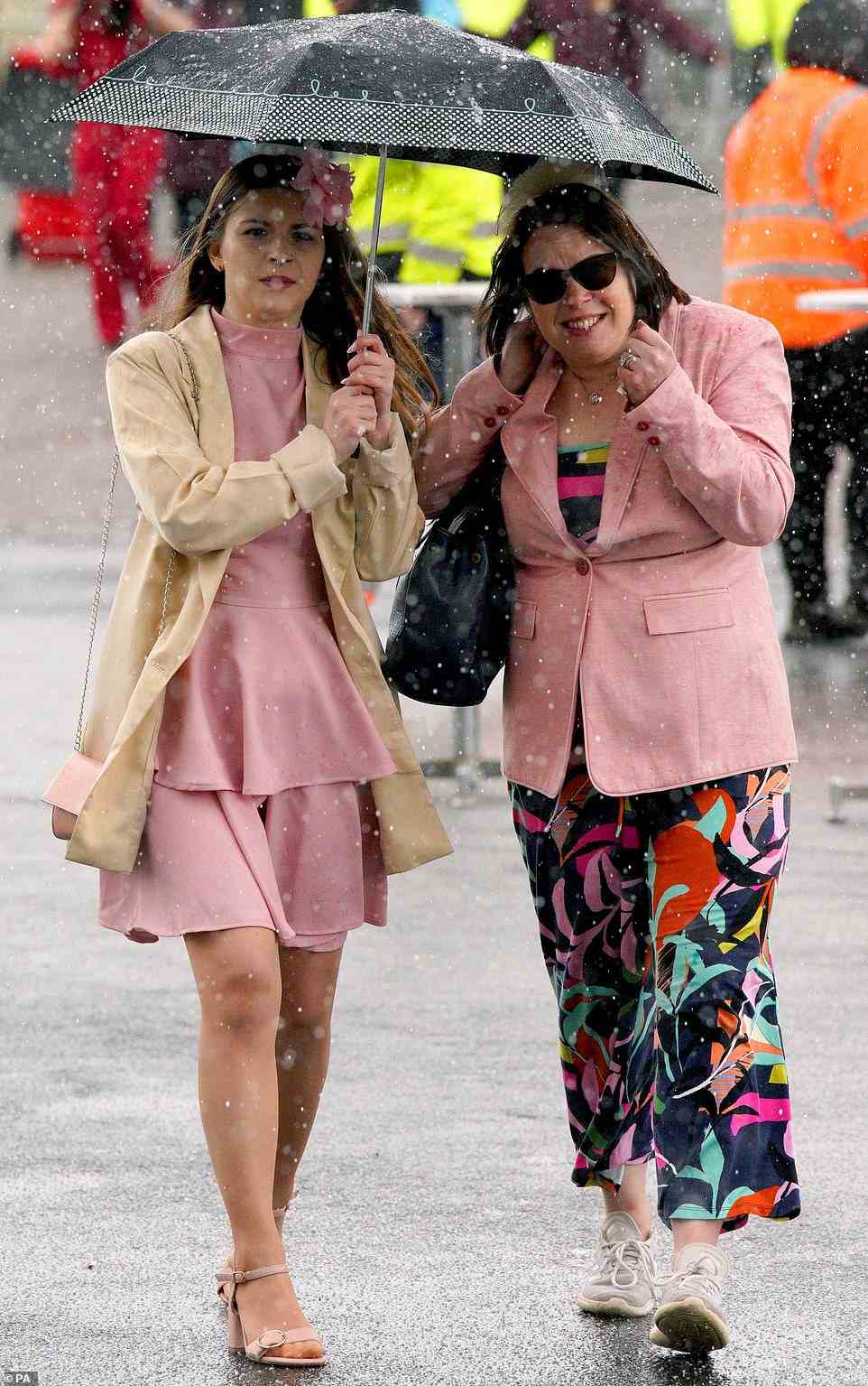 Racegoers do their best to look upbeat in the face of unrelenting rain, as they arrive at Aintree today for the third day of the event