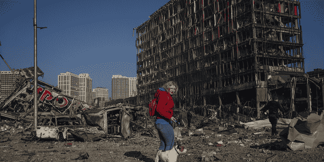 Irina Zubchenko geht mit ihrem Hund Max durch die Zerstörung, die am Montag nach dem Beschuss eines Einkaufszentrums in Kiew, Ukraine, angerichtet wurde.